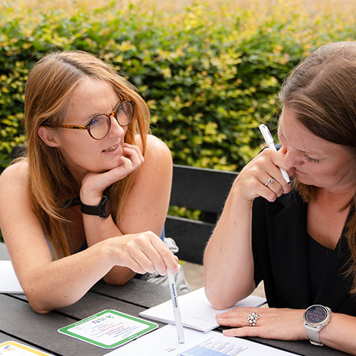 To kvinder taler sammen til konference om arbejdsmiljø