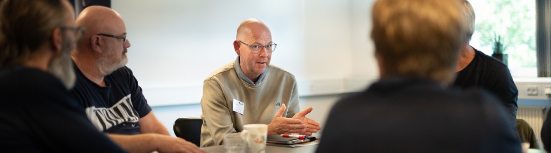 En gruppe af mennesker, der sidder og kommunikerer om arbejdsmiljø