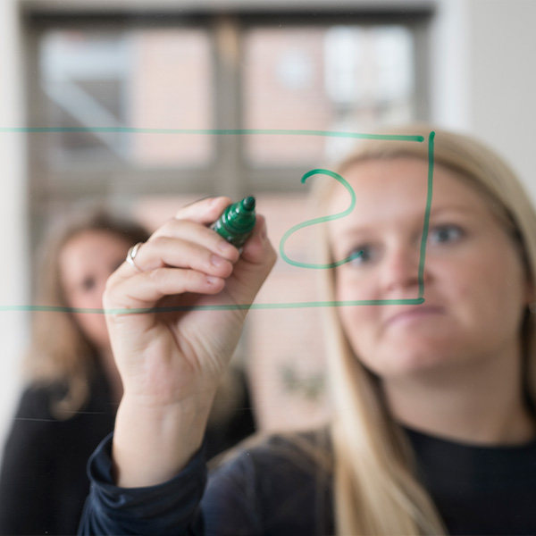 Konsulent fra Human House skriver på tavle og rådgiver om forandringsledelse