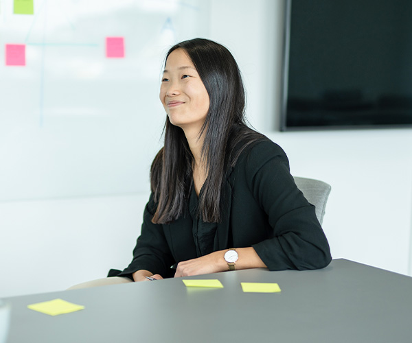 Smilende kvinde laver noter på post-its om generationsledelse