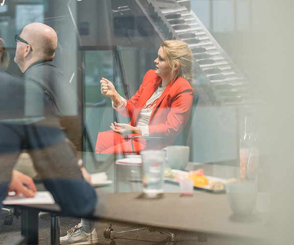 Kvinde i rødt jakkesæt taler om onboarding