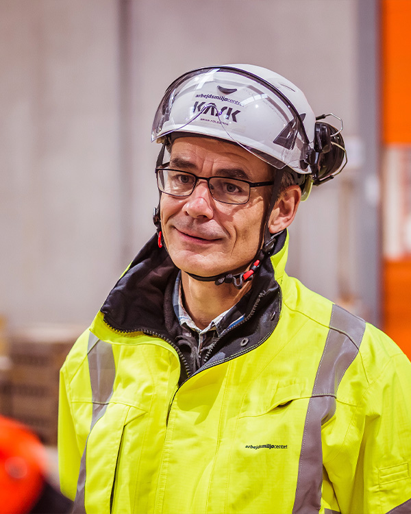 Glad mand der smiler med arbejdshjelm i bygge og anlægsbranchen